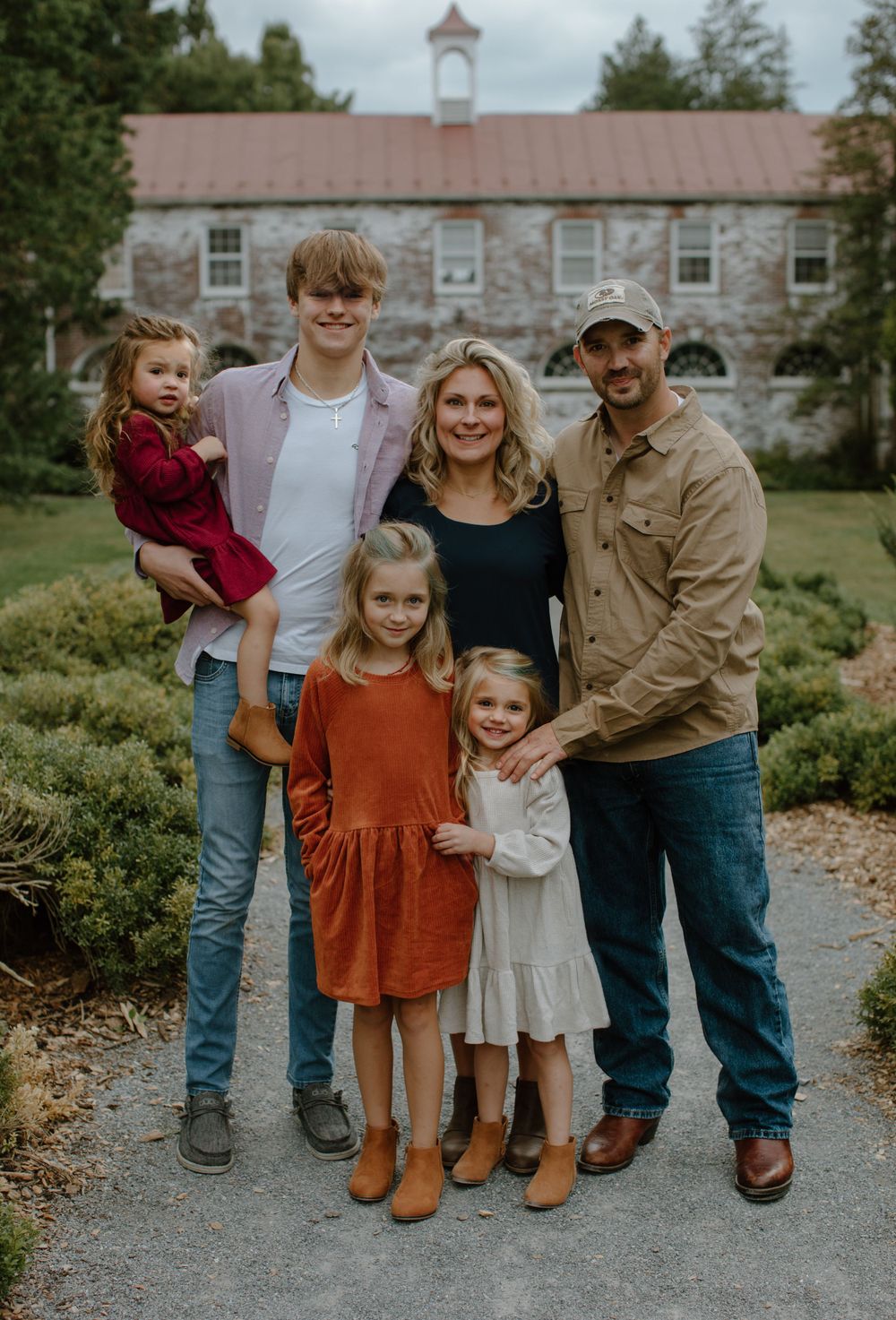Family portrait outdoors with stone building and church steeple in background.