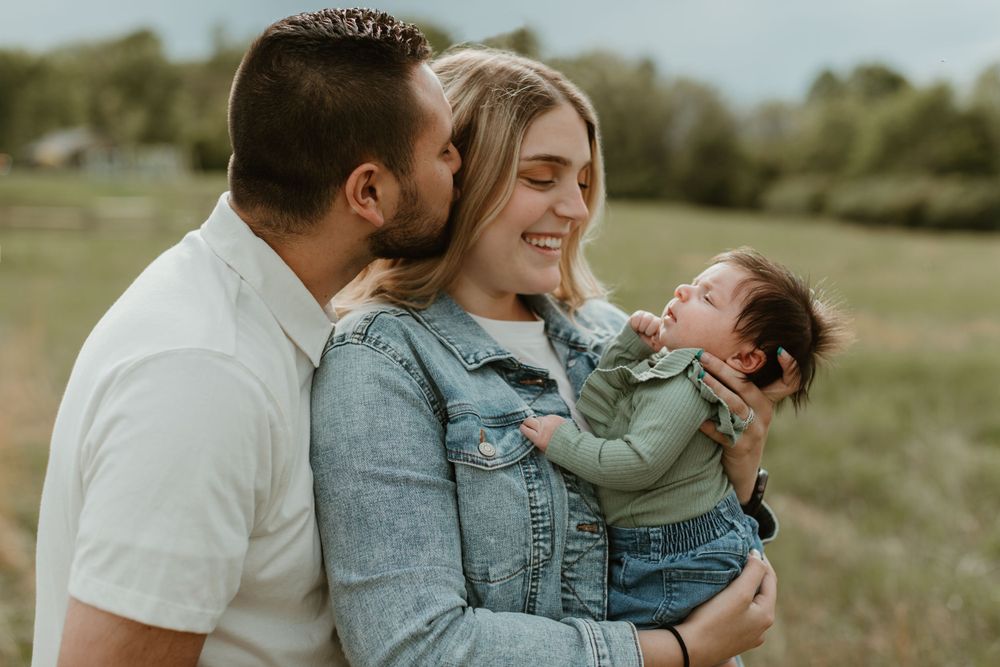 Family shares playful moments together during outdoor photo session in green field.