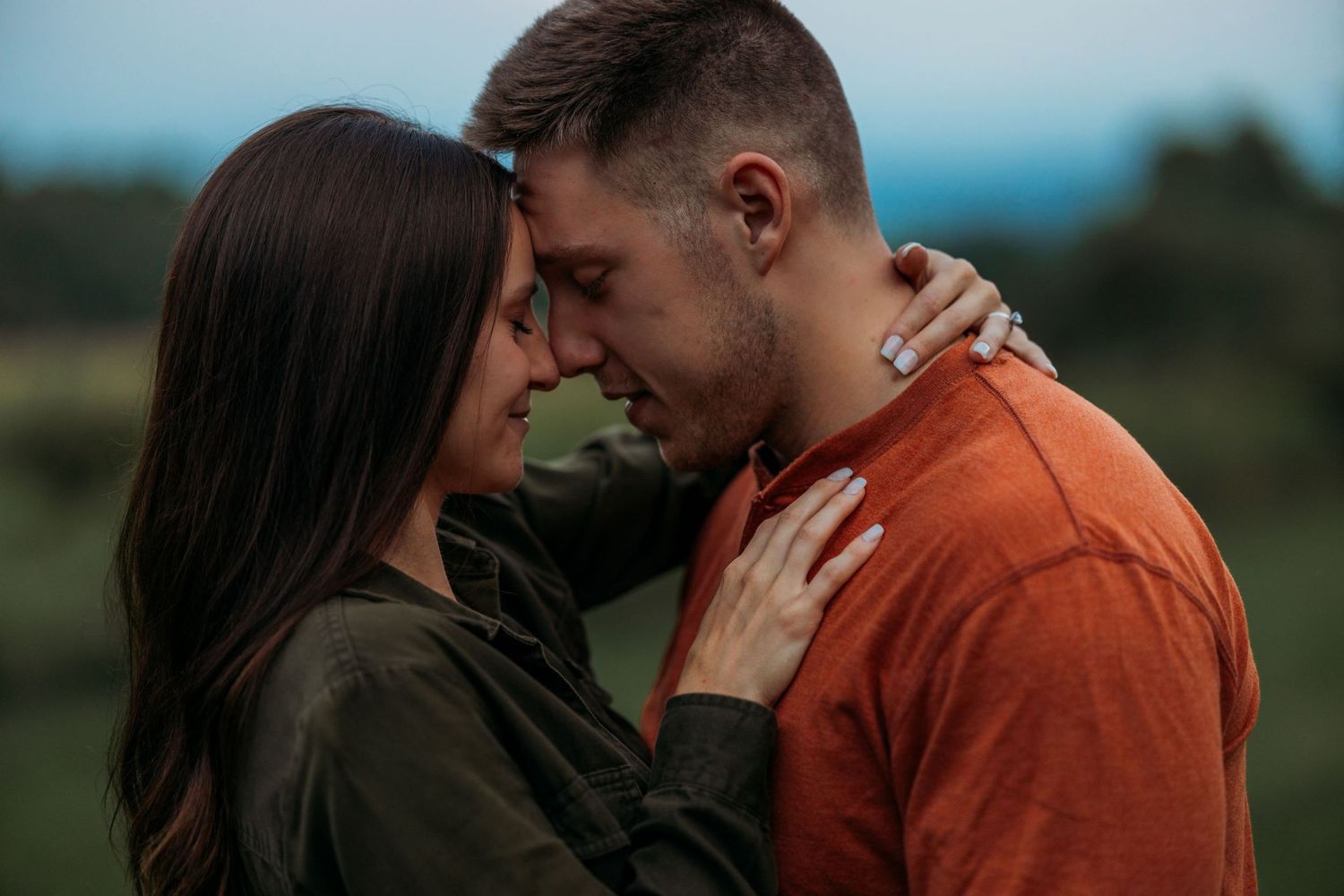 Couple in casual wear sharing intimate moment during outdoor photo session.