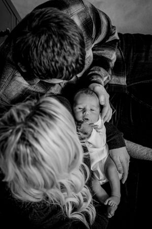Black and white image of parents looking down at their newborn baby.