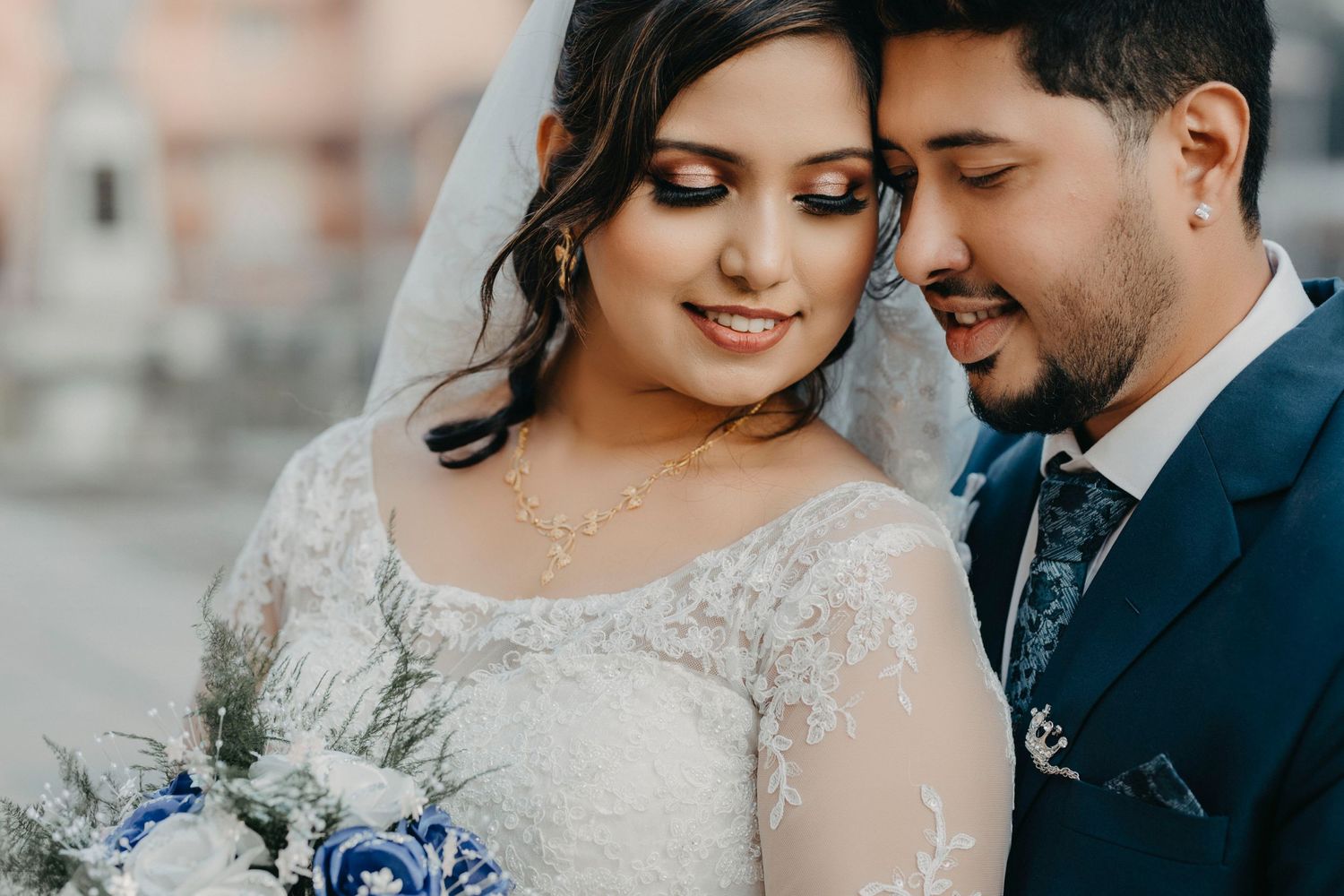 Close-up of couple sharing tender moment with blue wedding bouquet.