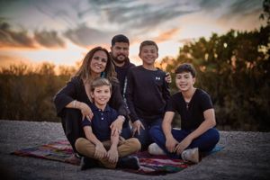 Family group sitting together outdoors during golden sunset hour.