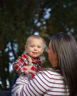 Sweet interaction between parent and baby in red plaid shirt against natural background.