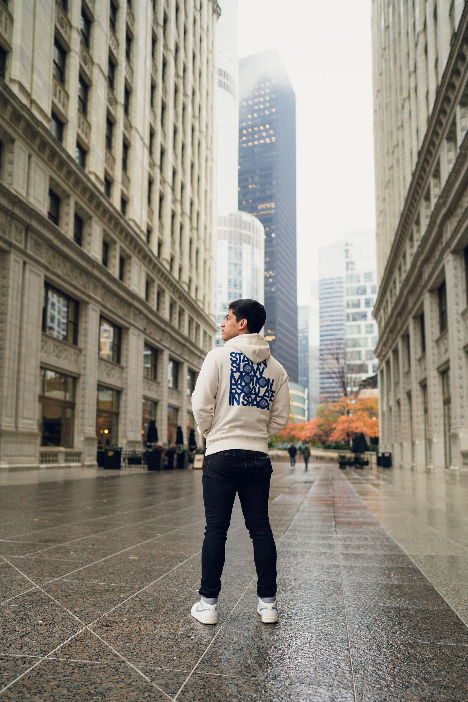 Person in casual wear walking through urban architecture with skyscrapers in background.