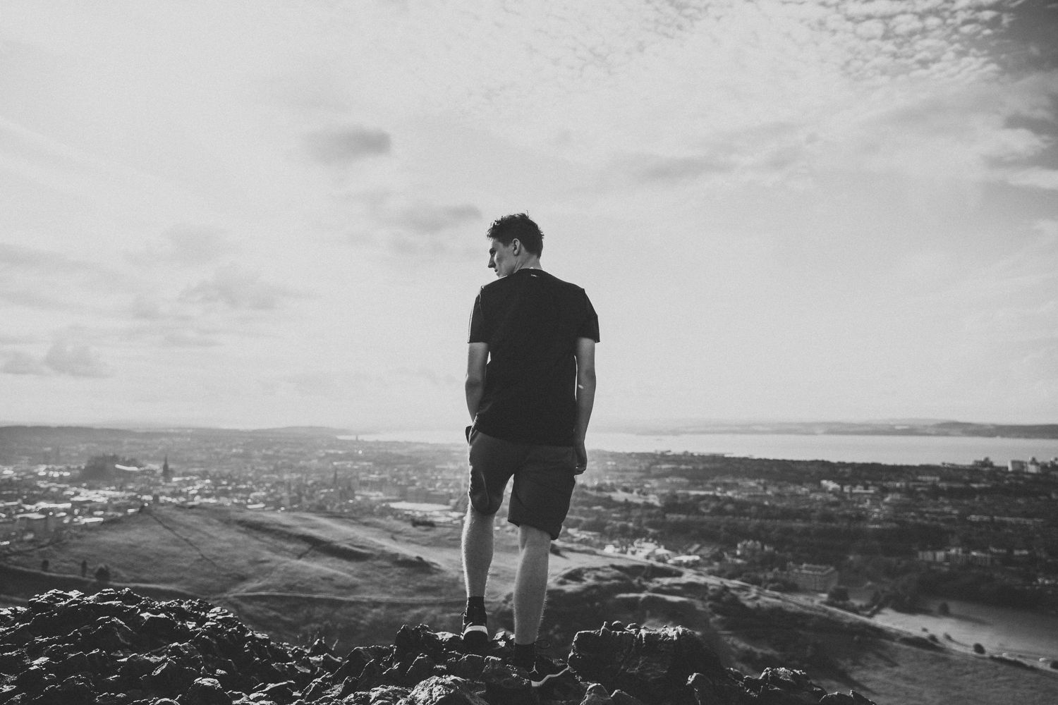 Silhouette of someone standing at a scenic hilltop overlook against a dramatic cloudy sky.