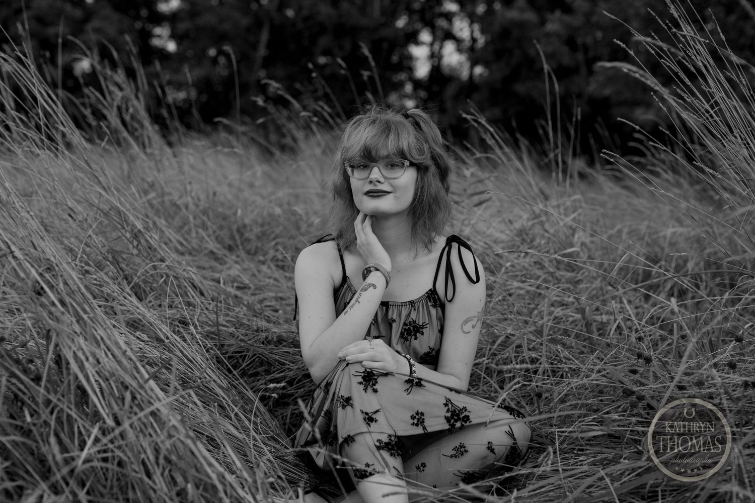 Black and white field portrait with floral dress among tall grass.