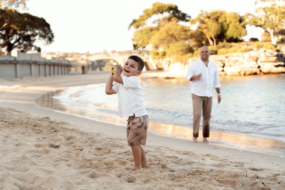 boy throwing a ball at the mosman beach during family photoshoot