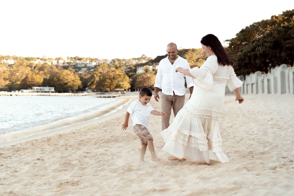 Family plays football during family photoshoot at balmoral beach