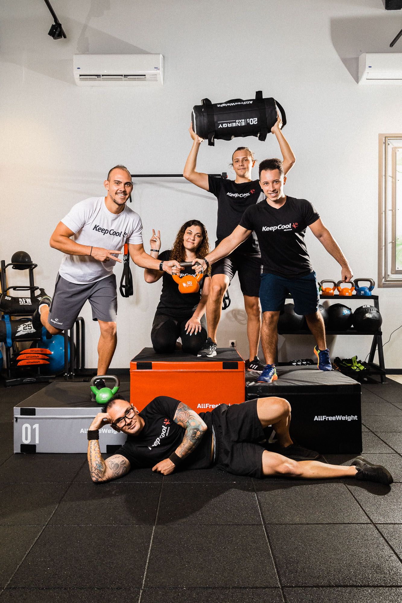 Group fitness session with people exercising on gym mats and equipment in a modern training facility.