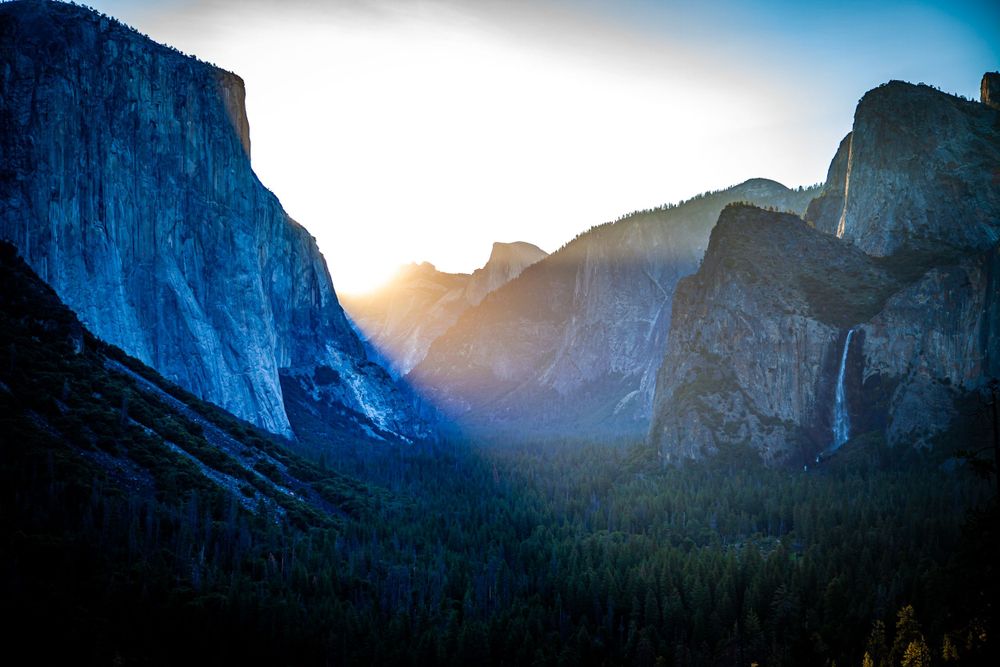 Sunset illuminates Yosemite Valley's iconic cliffs and waterfalls in golden light.