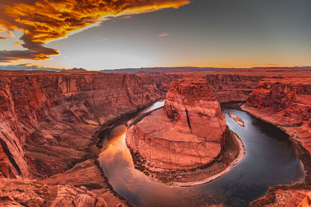 Horseshoe Bend glows with vibrant orange hues during sunset as the Colorado River curves through deep canyon walls.