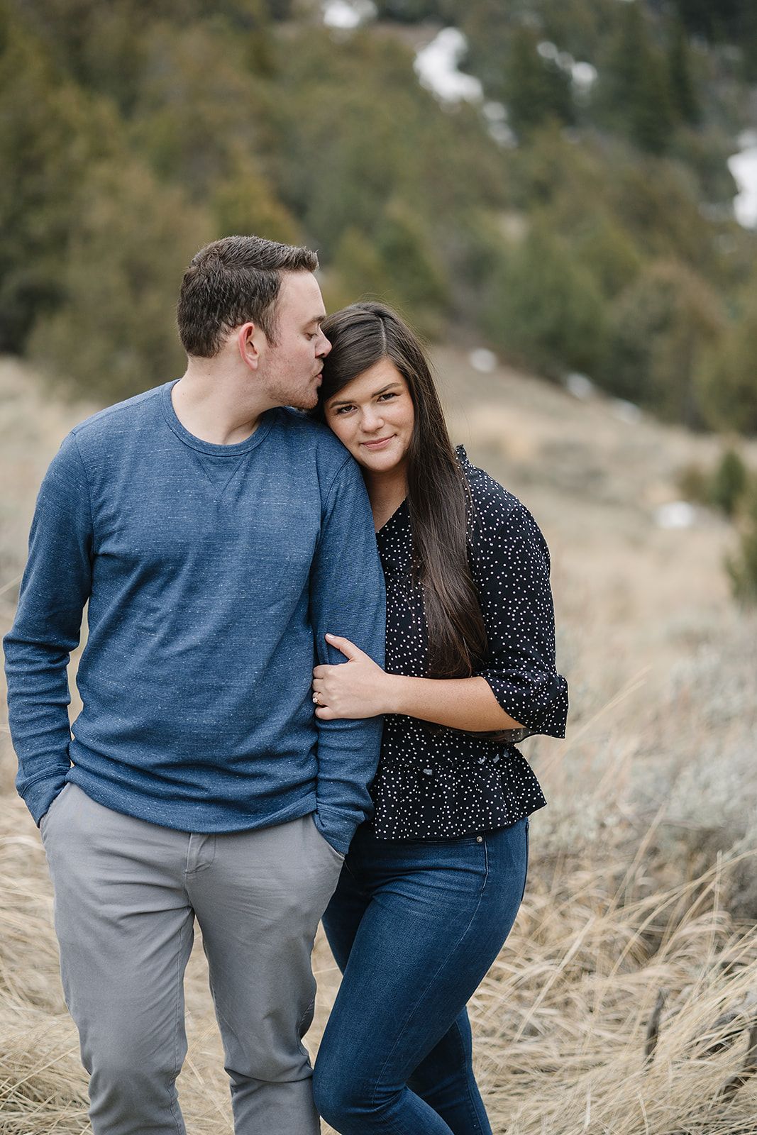 Intimate moment between couple on mountainside with winter landscape.