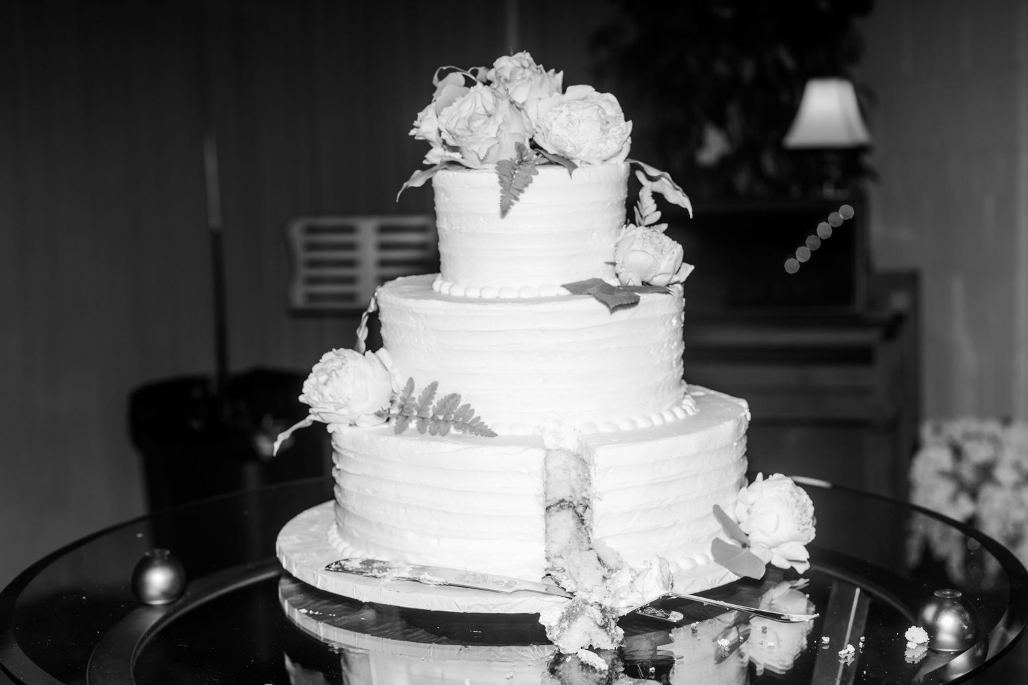 Black and white photo of a multi-tiered wedding cake decorated with white roses.
