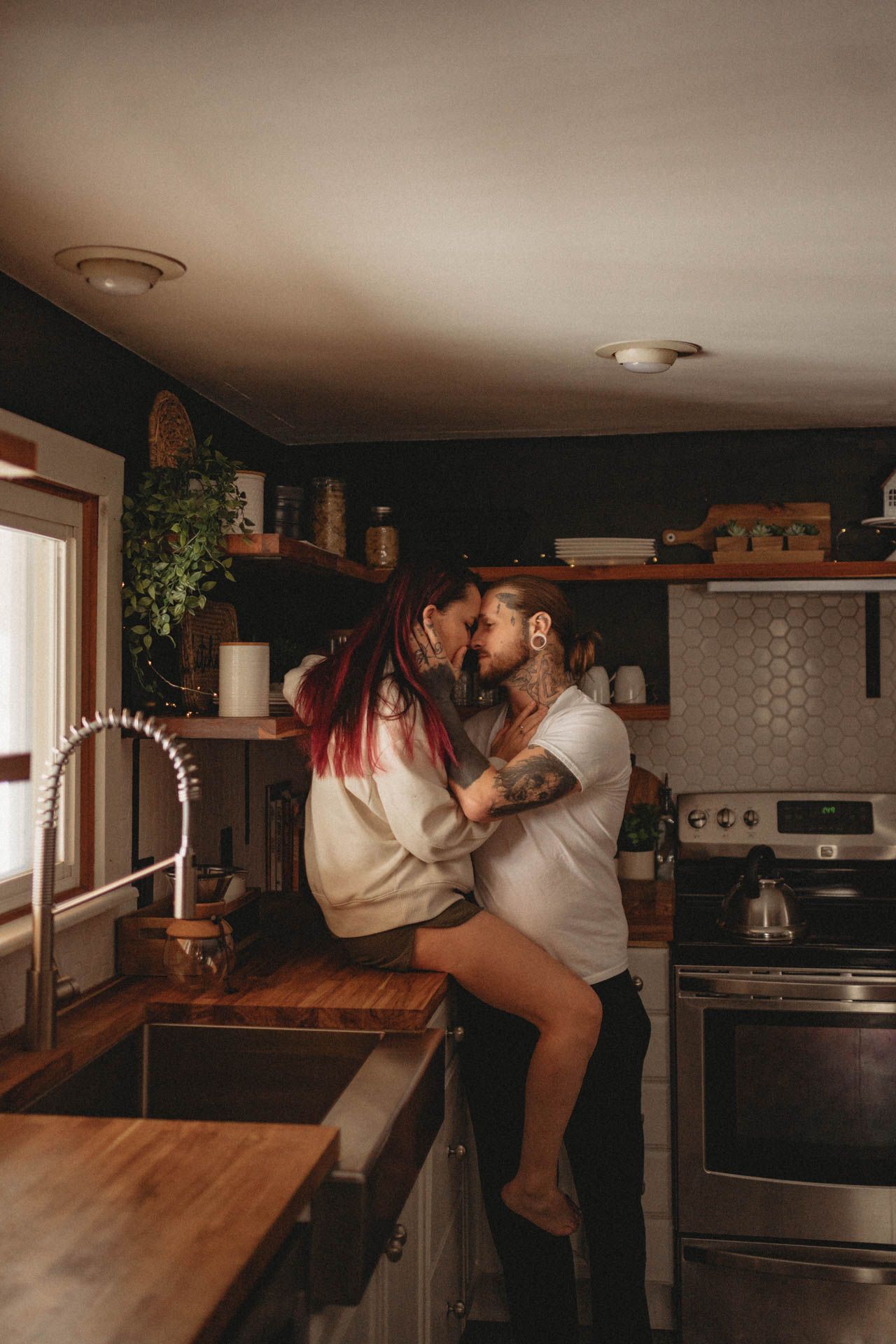Romantic moment shared between couple in cozy kitchen with wooden countertops and warm lighting.