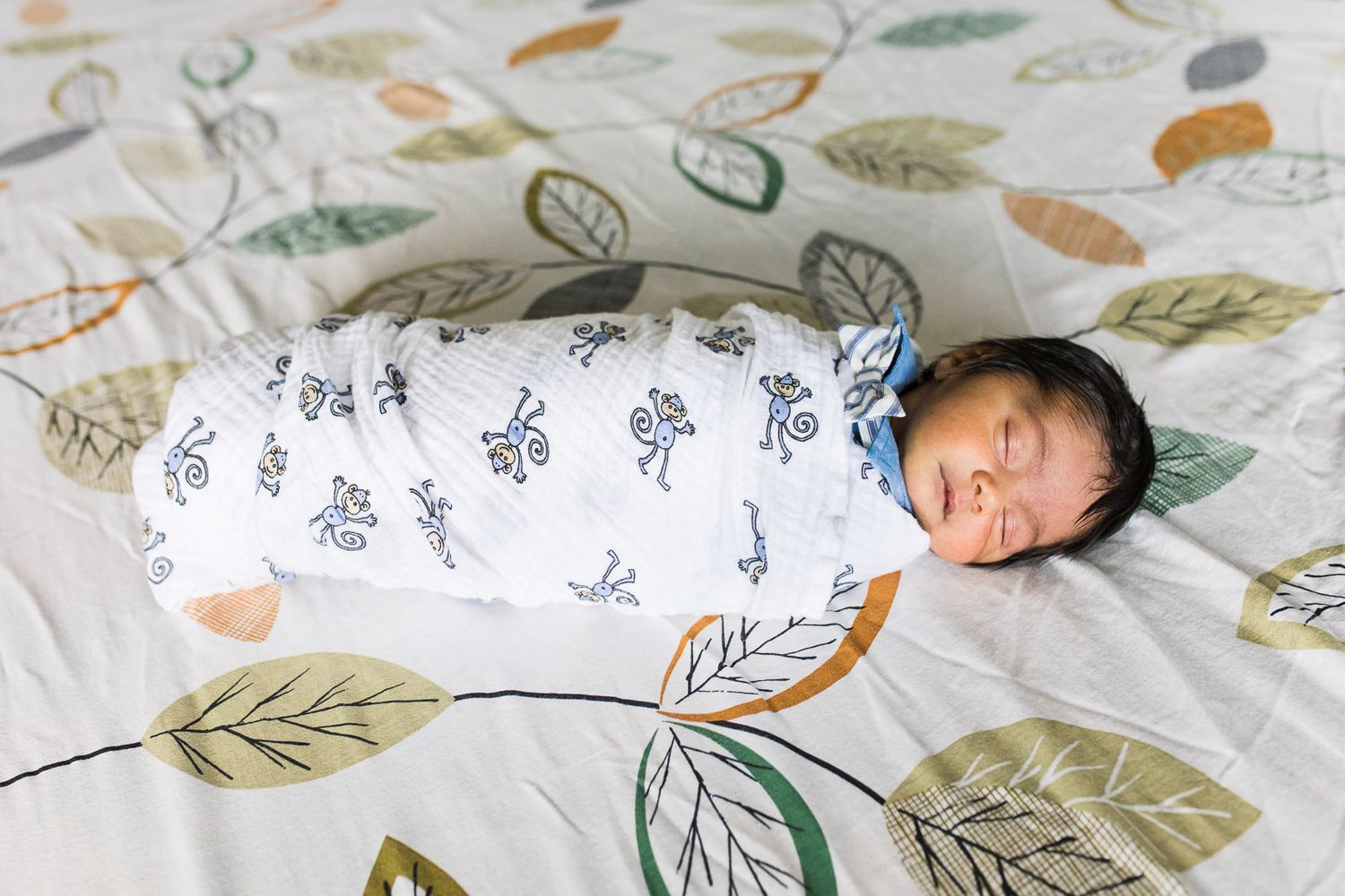 Newborn swaddled and laying on their bed