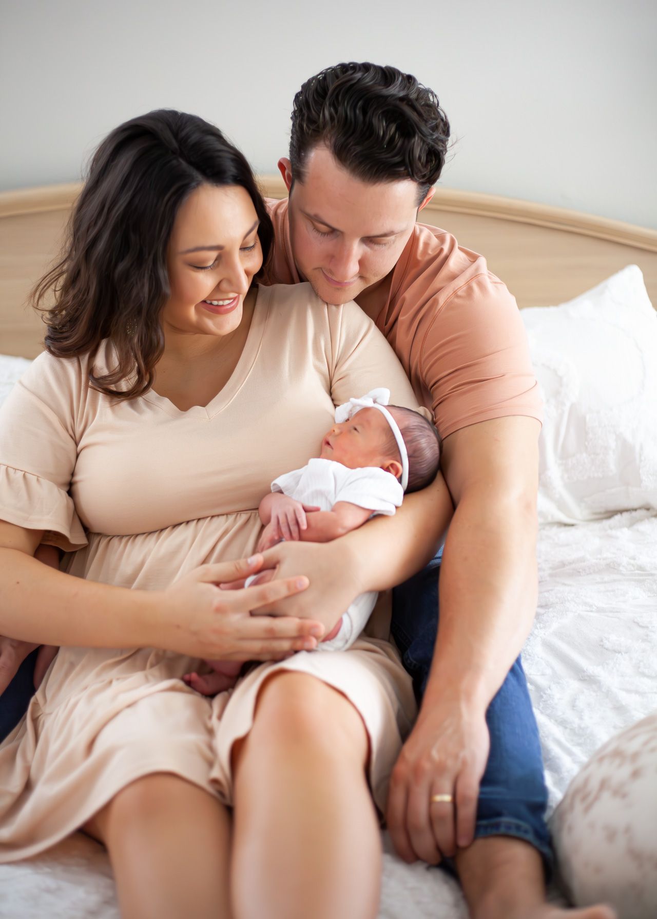 Intimate newborn lifestyle photography session on white bedding.