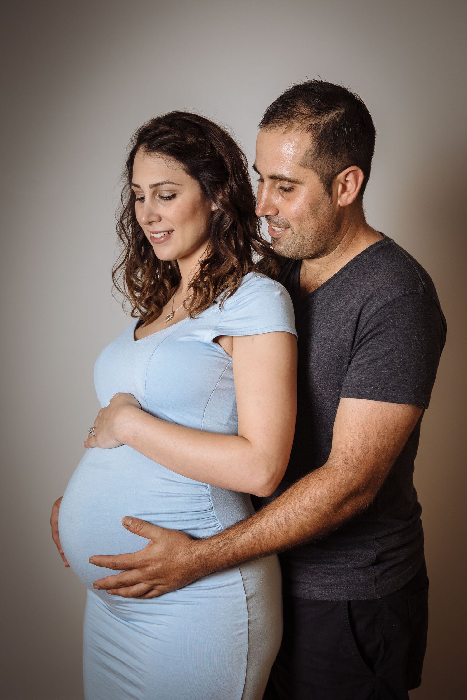 Couple holding eachother and pregnant belly