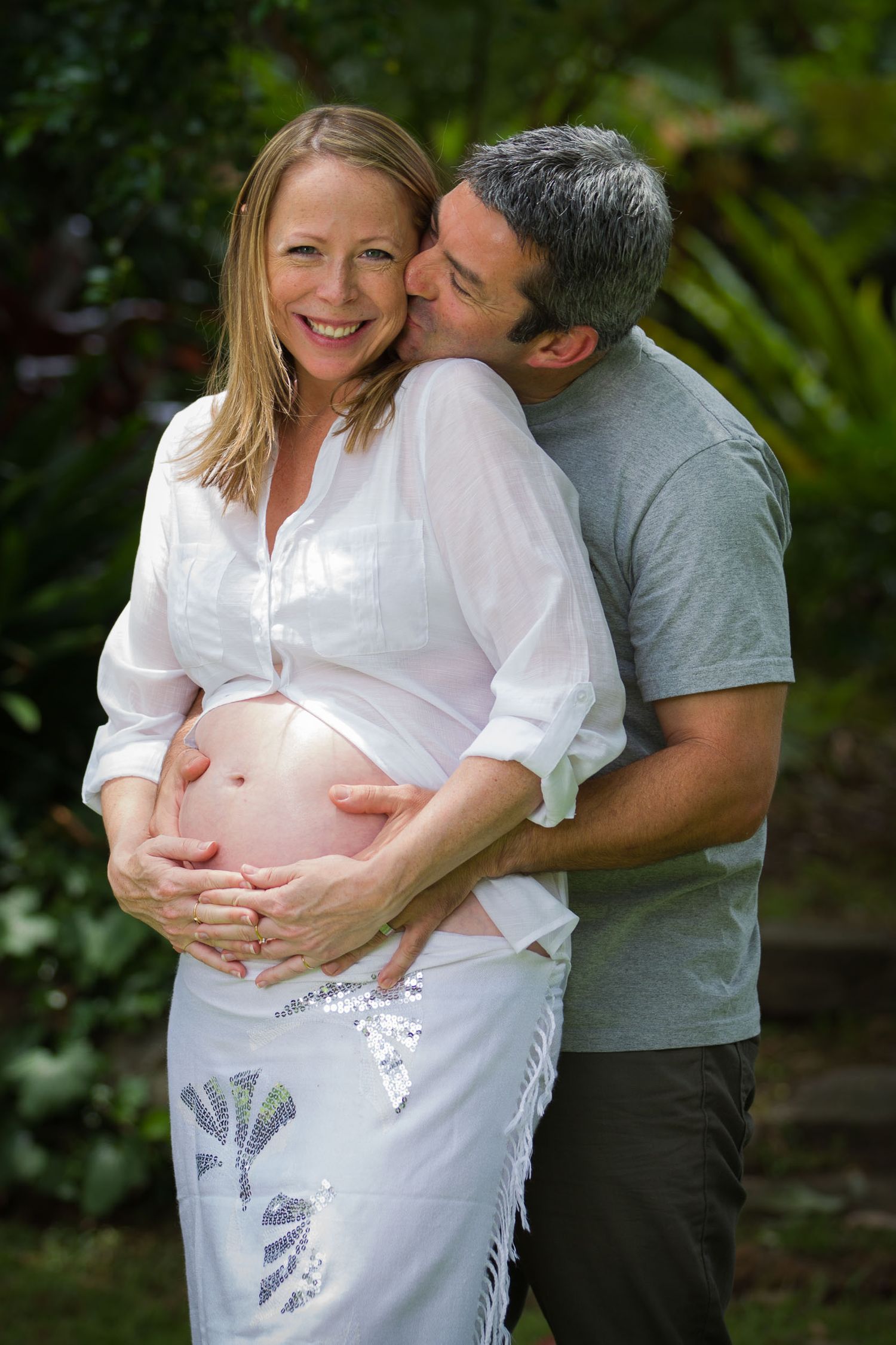 Dad kissing mum holding pregnant belly