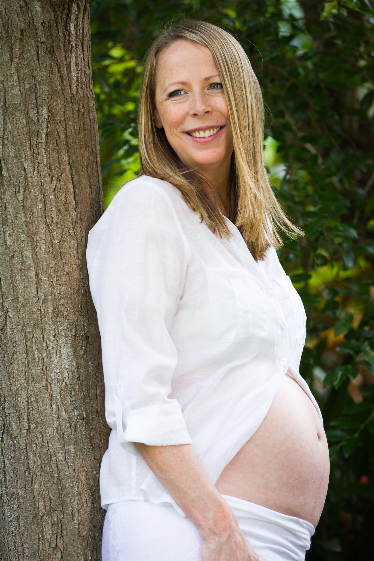 Mum resting against tree showing pregnant belly