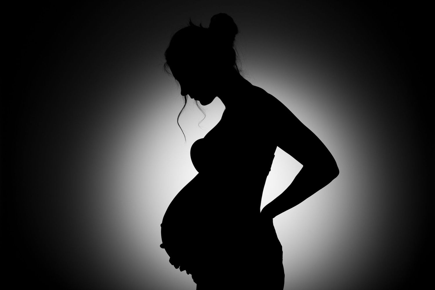Silhouette of pregnant lady looking down at baby