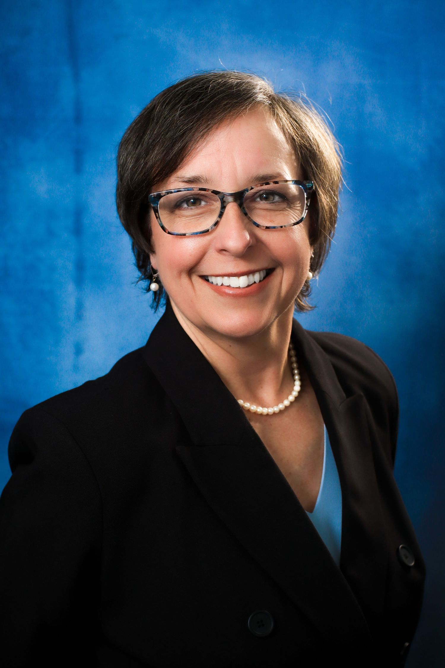 Woman in suit smiling in front of camera