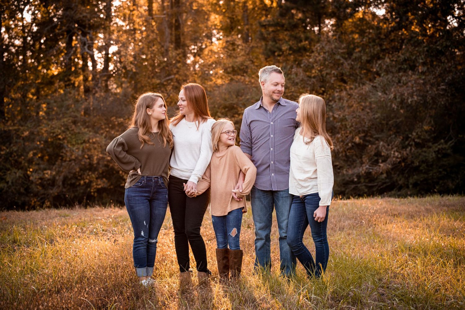 mother father and daughters in a field at golden hour