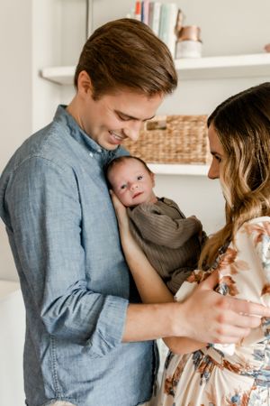 New parents share tender moment with newborn baby in home setting.