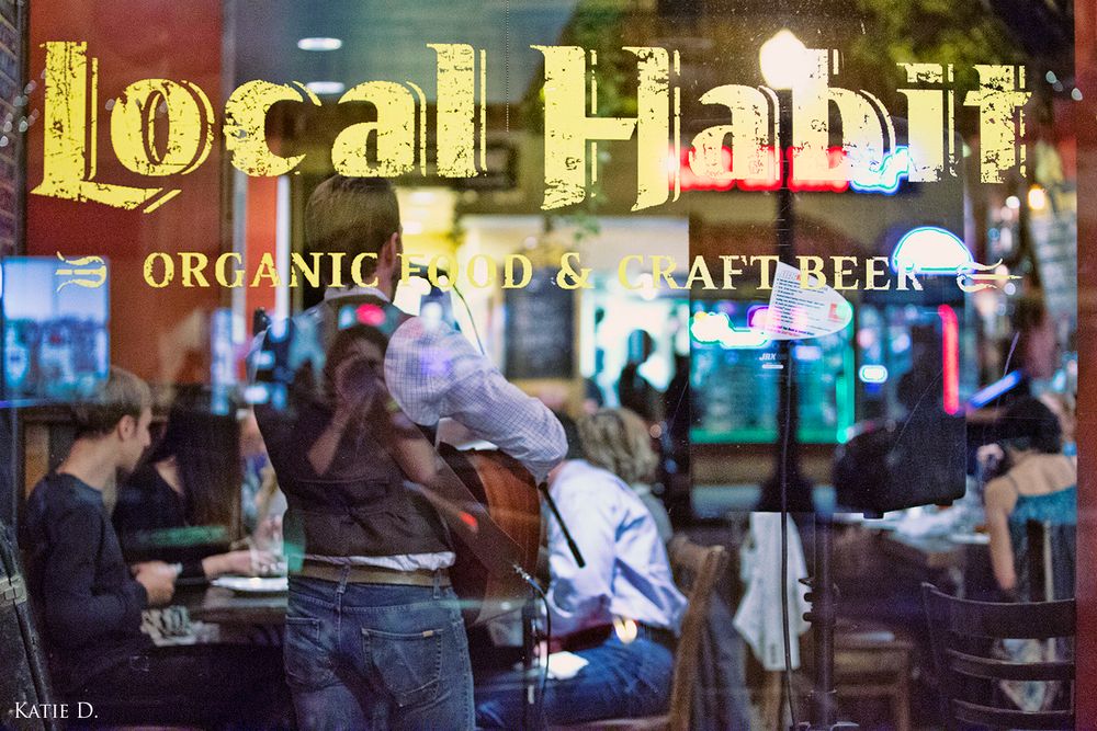 Local Habit organic food and craft beer restaurant sign reflected in front window at night.