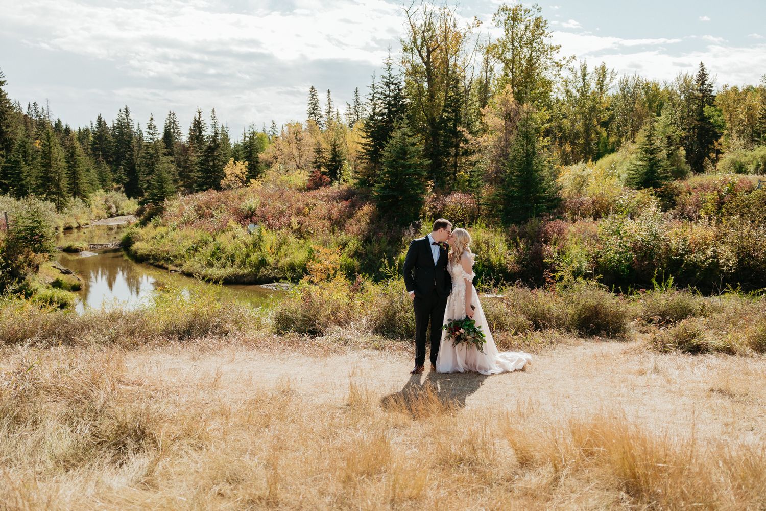 Newlywed couple standing together in scenic mountain landscape.