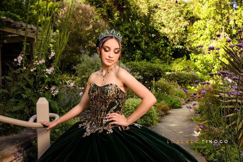 Strapless black ball gown with gold details photographed in landscaped garden setting.