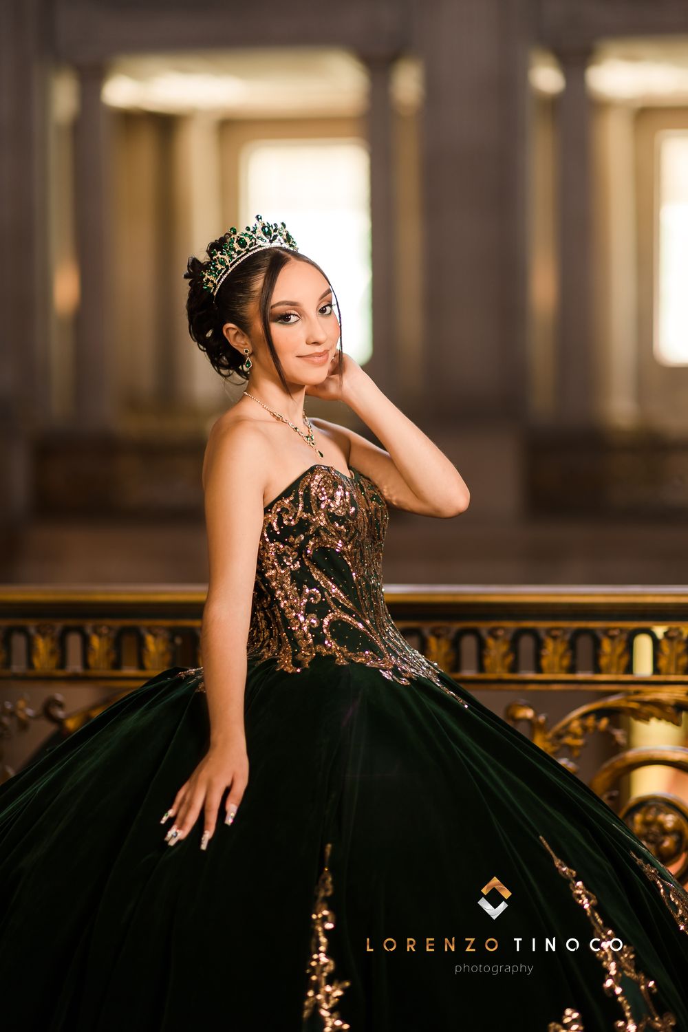Elegant dark ball gown with intricate gold details photographed in a grand hallway setting.