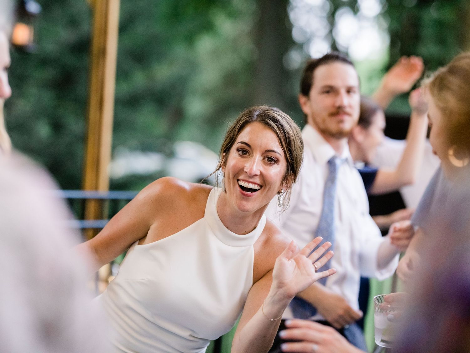 bride waves to camera during backyard reception