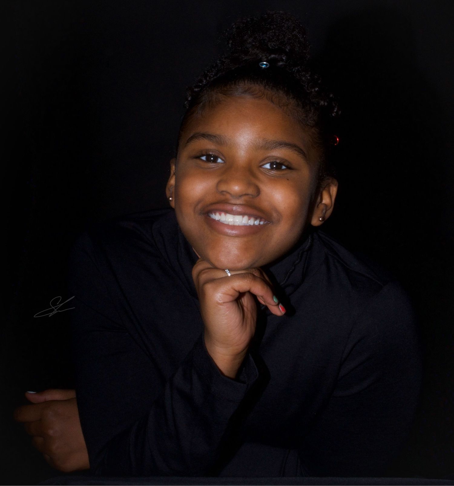 Studio portrait of someone in navy top against dark background with radiant smile.