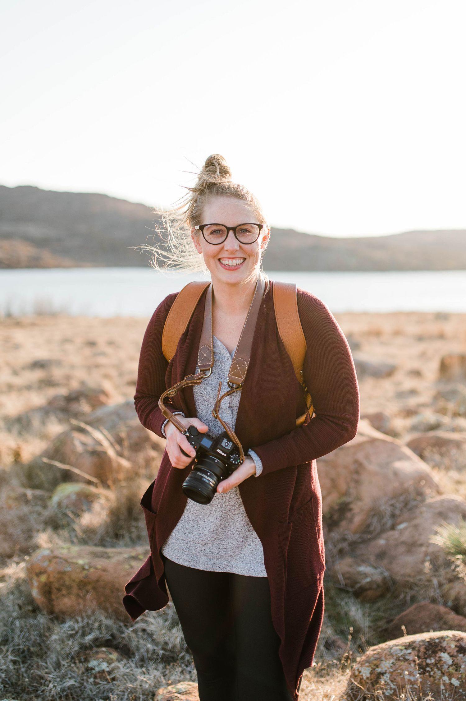 Carolyn Stonewheel Photography a Dallas area family photographer poses with her Nikon camera in the Oklahoma mountains