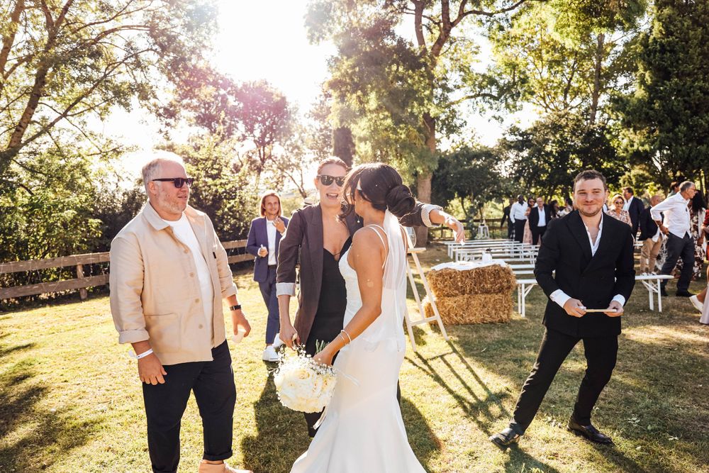 Wedding guests celebrating outdoors during golden hour with joyful dancing.