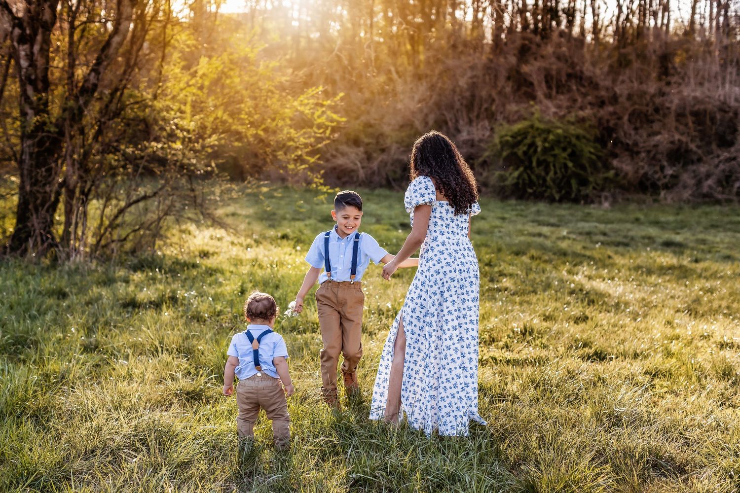 Family walking through a sunlit meadow during golden hour.