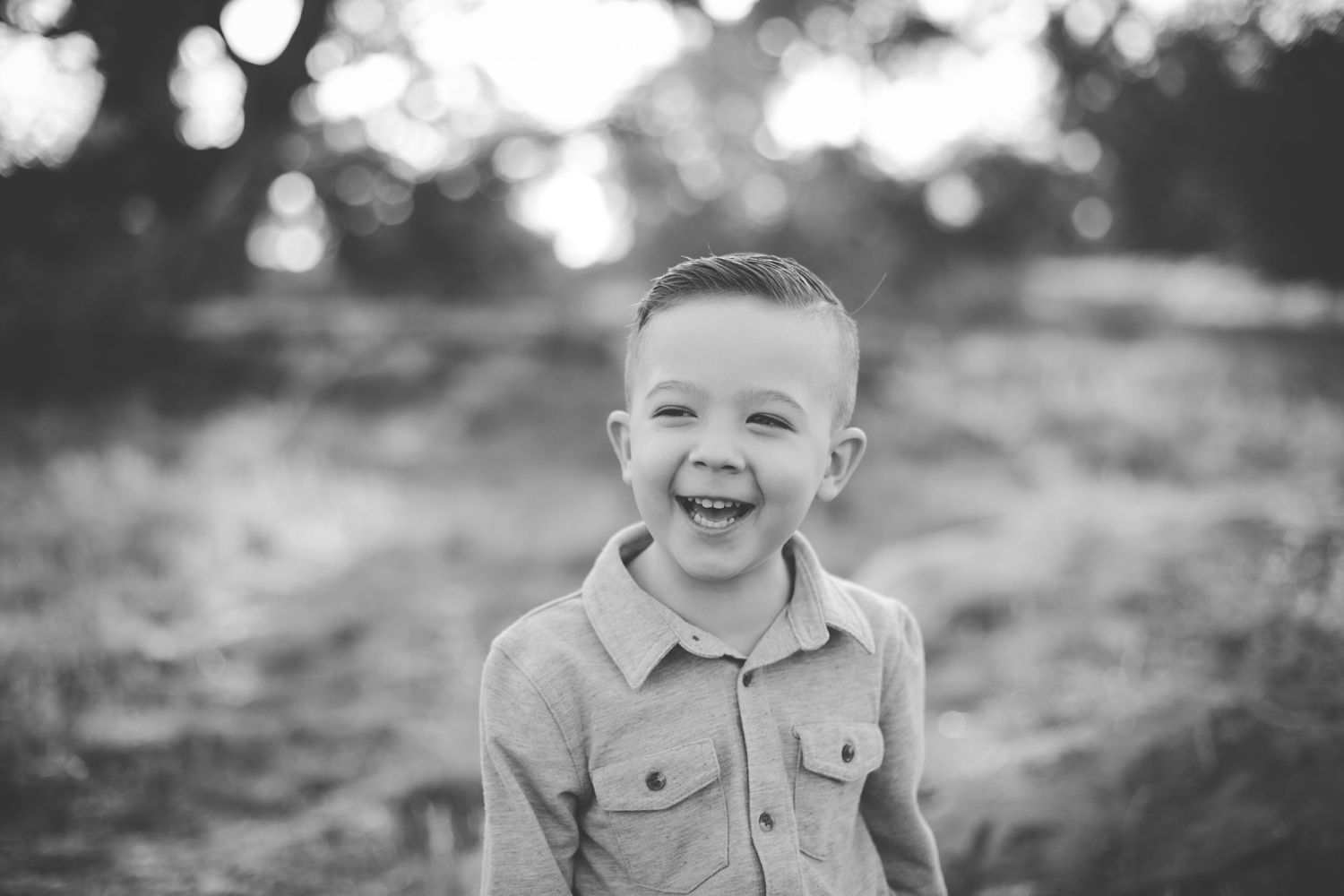 A black and white portrait captures pure joy and laughter in a natural outdoor setting.