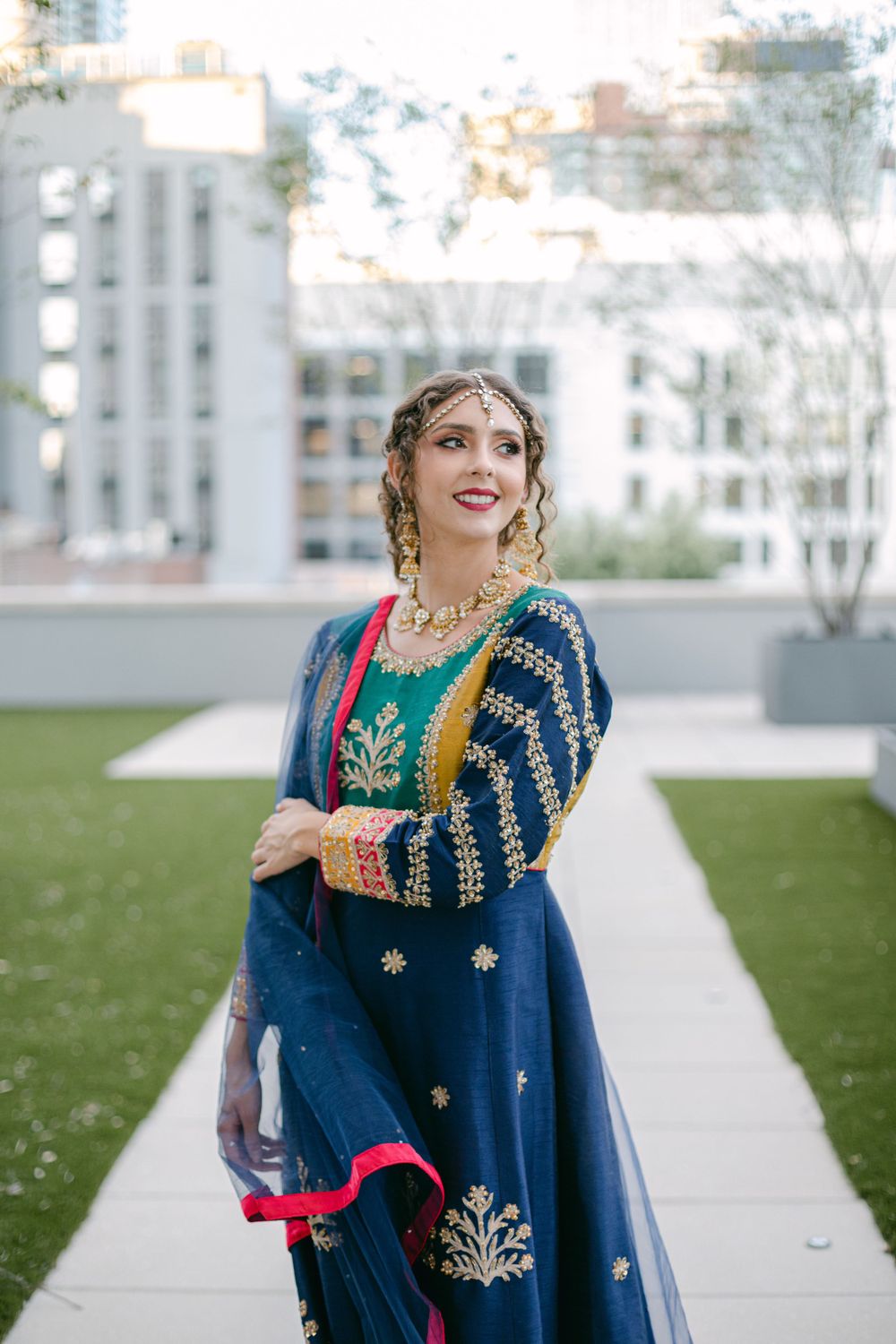 Traditional navy blue and gold embroidered outfit photographed in modern rooftop garden setting.