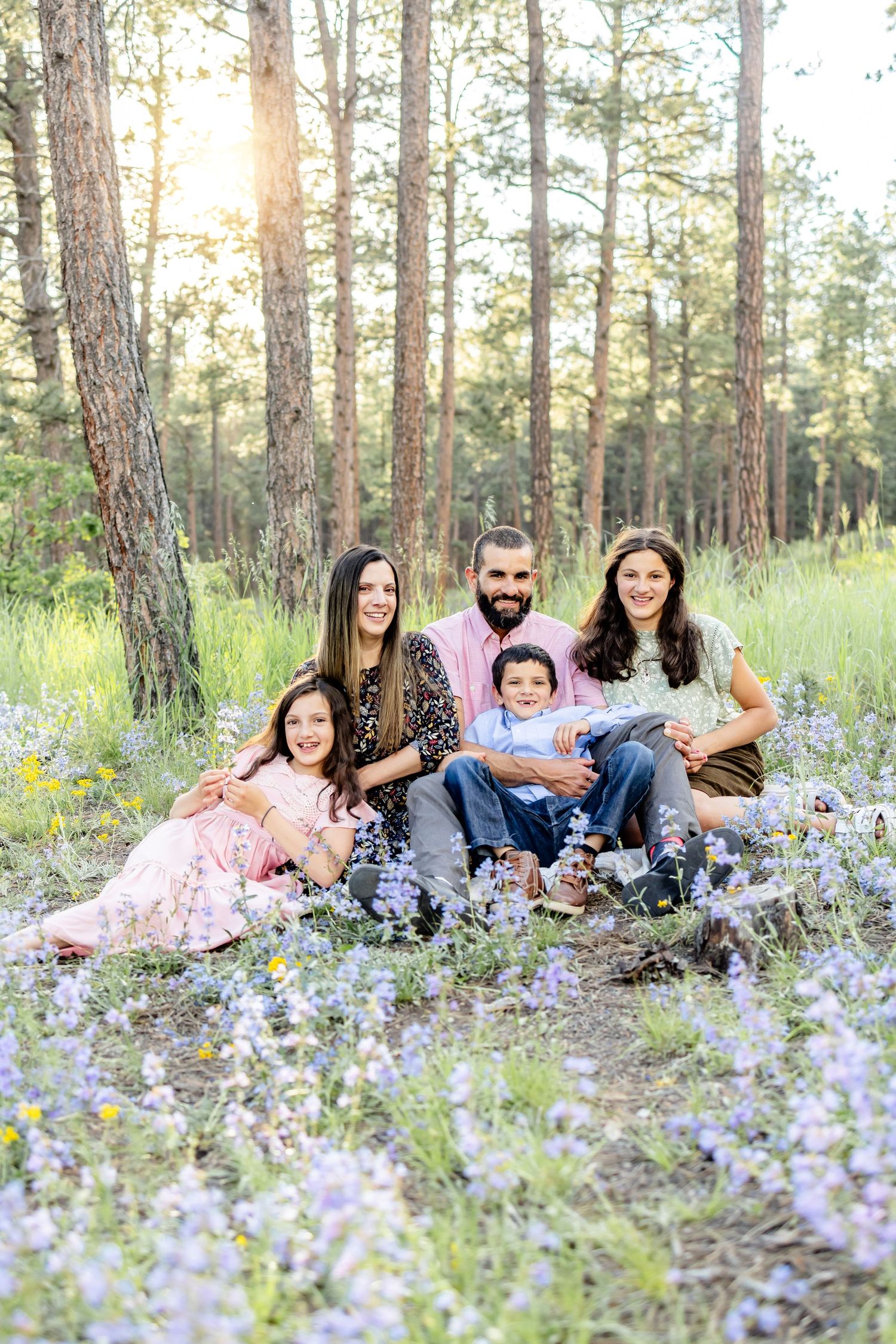 Parents and their three children smile among the wildflowers during their family session in Colorado Springs.