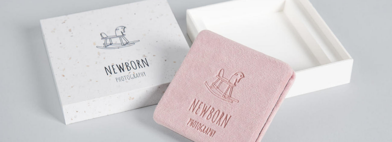 Elegant wedding photo albums in white and pink with embossed designs.