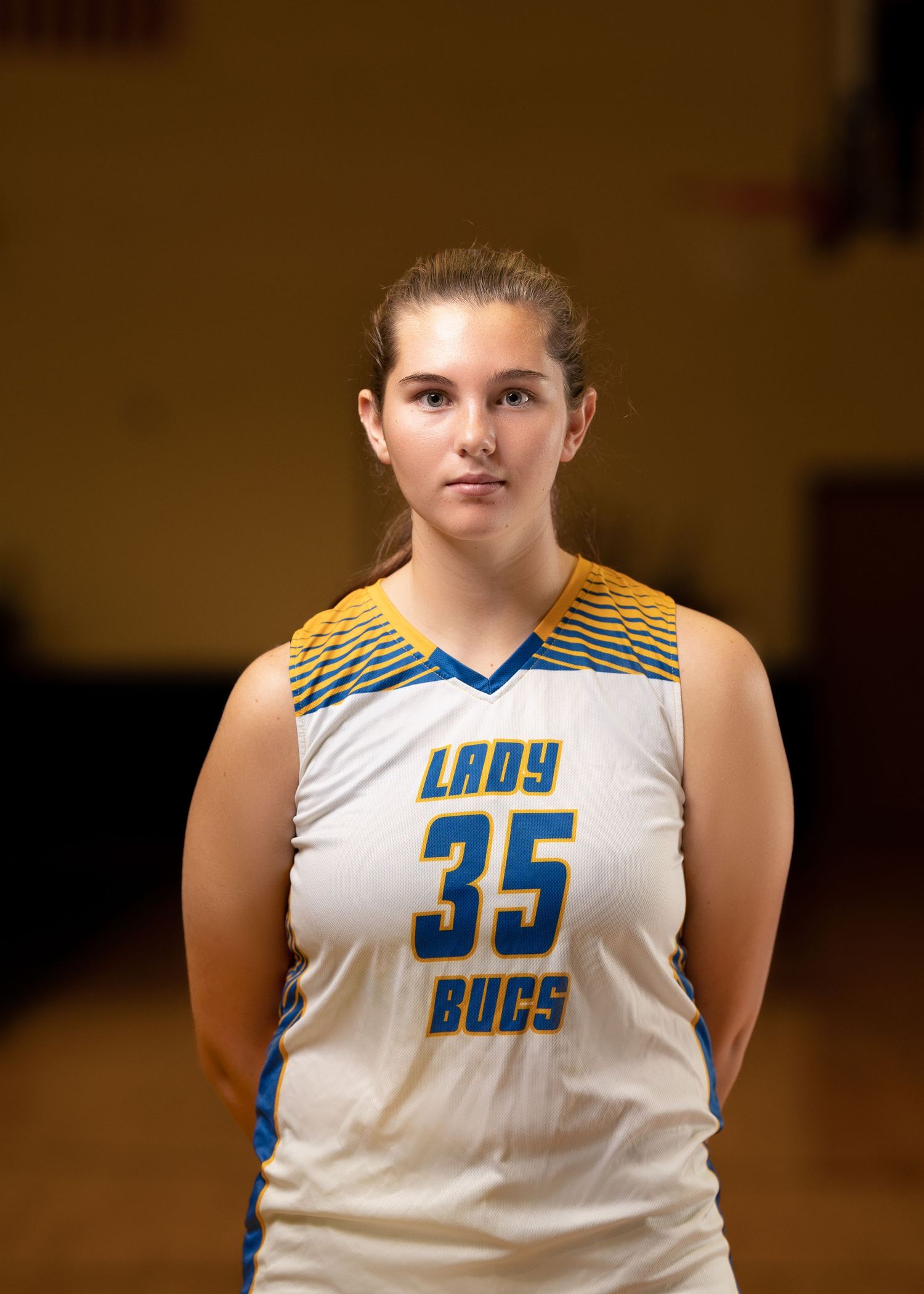 Basketball player in white Lady Bucs uniform number 35 stands for team photo.