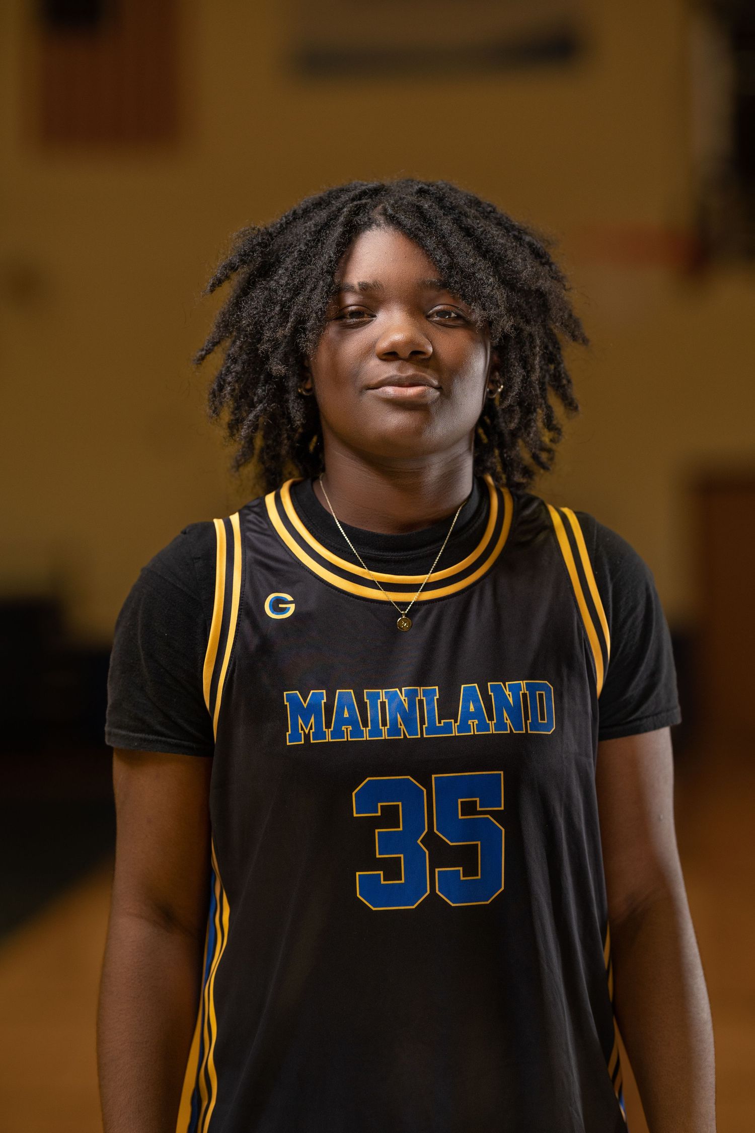 Basketball player in black Mainland jersey number 35 poses against warm-toned background.