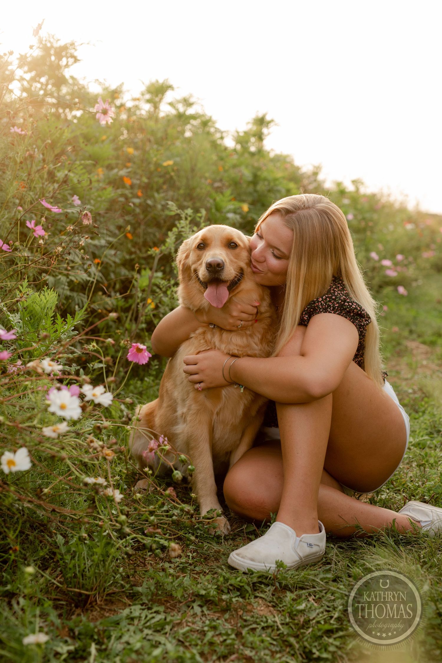 Joyful embrace with a smiling golden retriever in a garden filled with colorful wildflowers.