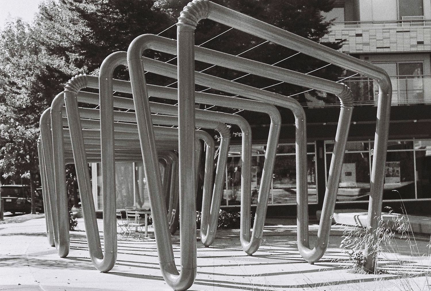 Modern curved metal bike racks creating geometric patterns in black and white photography.