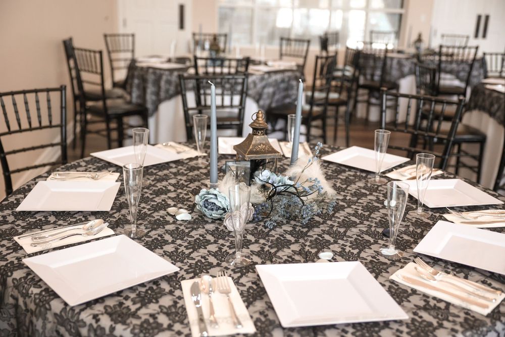 Reception tables with blue candle centerpieces and white place settings on brown damask tablecloths.