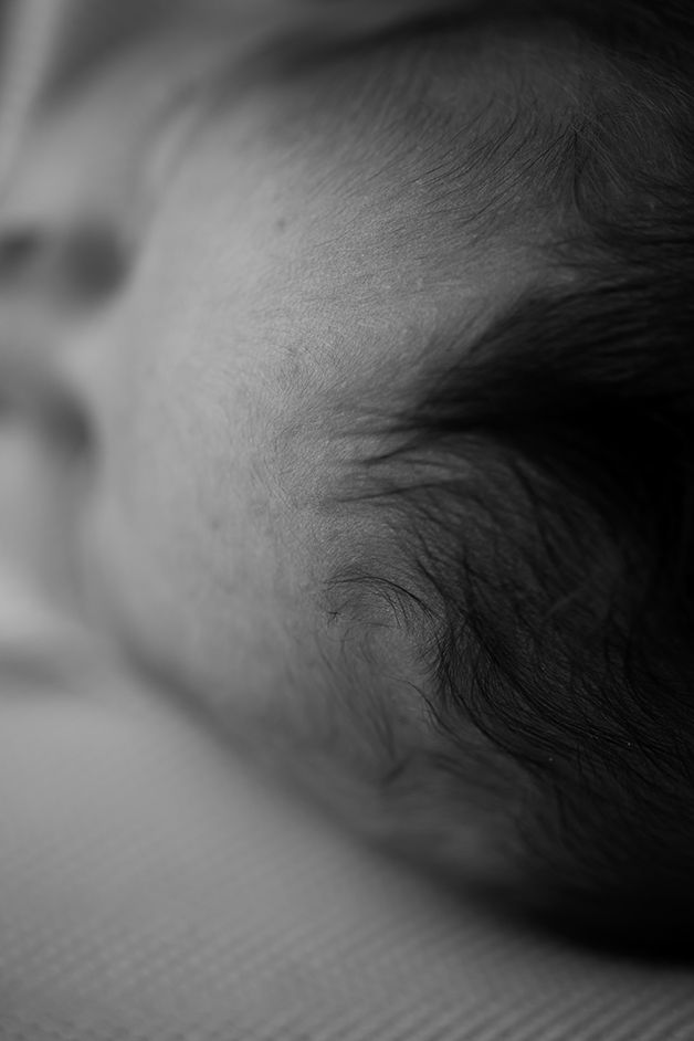 Close-up black and white detail of baby's head showing soft hair and skin texture.