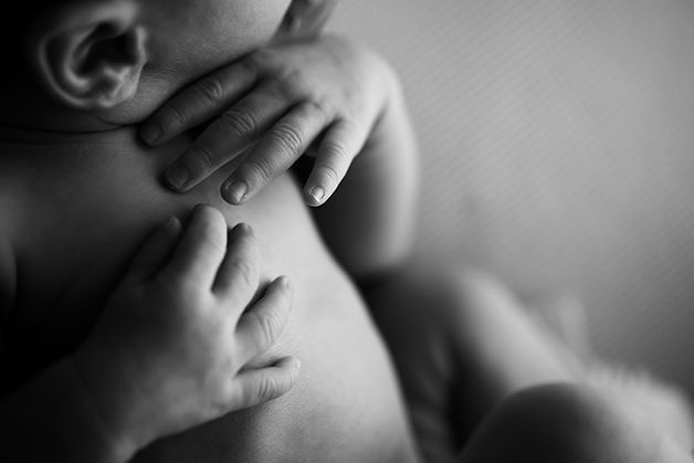 Intimate black and white capture of newborn's hand near face while sleeping.