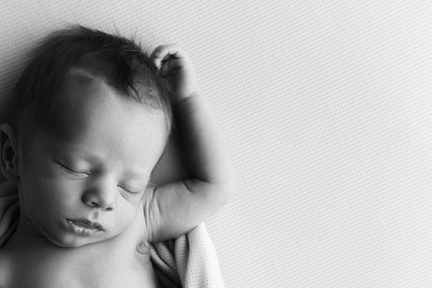 A peaceful black and white portrait of a sleeping infant with soft lighting.