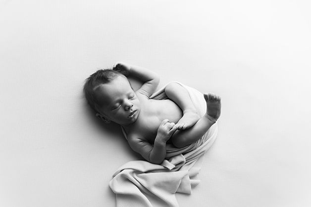 Newborn baby sleeping peacefully wrapped in soft white fabric.
