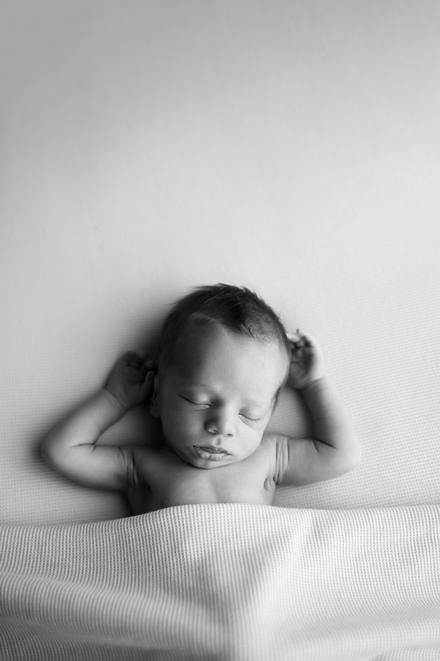 Artistic black and white portrait of sleeping baby on textured surface.